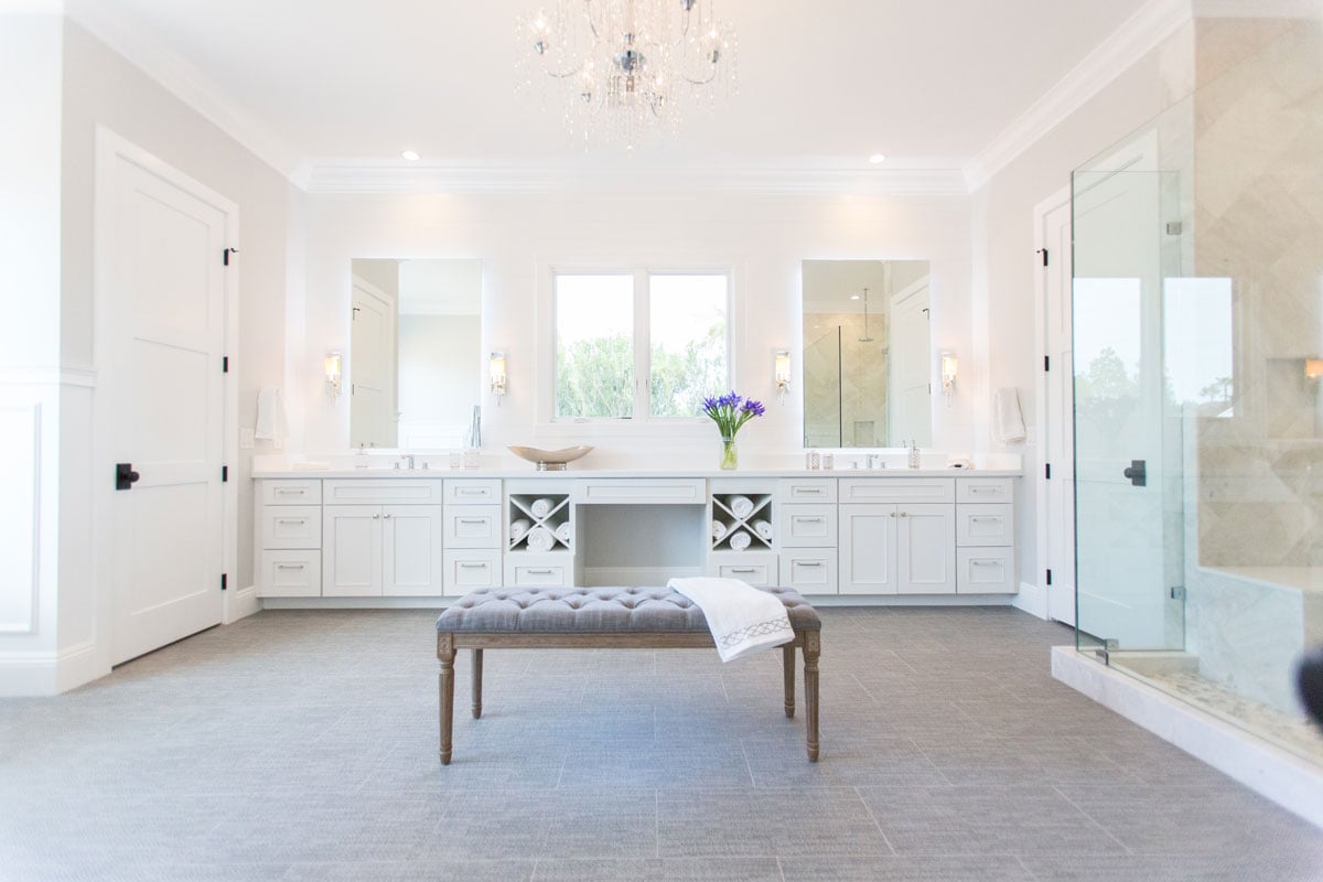 Full room view of white purity transitional bathroom with center bench
